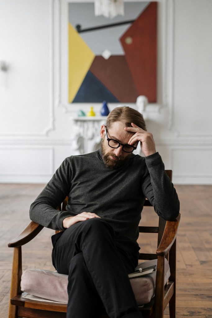 Man reflecting quietly indoors, representing the role of a lifestyle coach in lifestyle coaching and personal transformation.