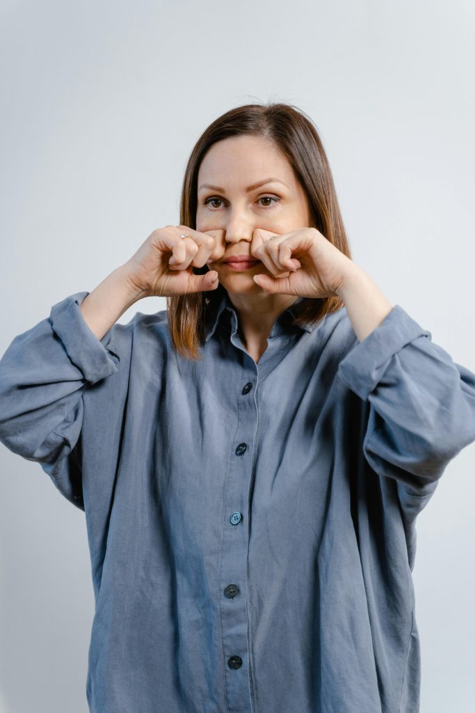 Woman performing anti aging facial exercise as part of Dr. Pat Boulogne’s anti aging facial treatment guide.