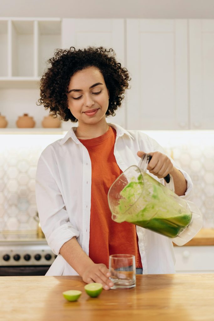 a lady making a green juice as advised by the certified nutritional coach